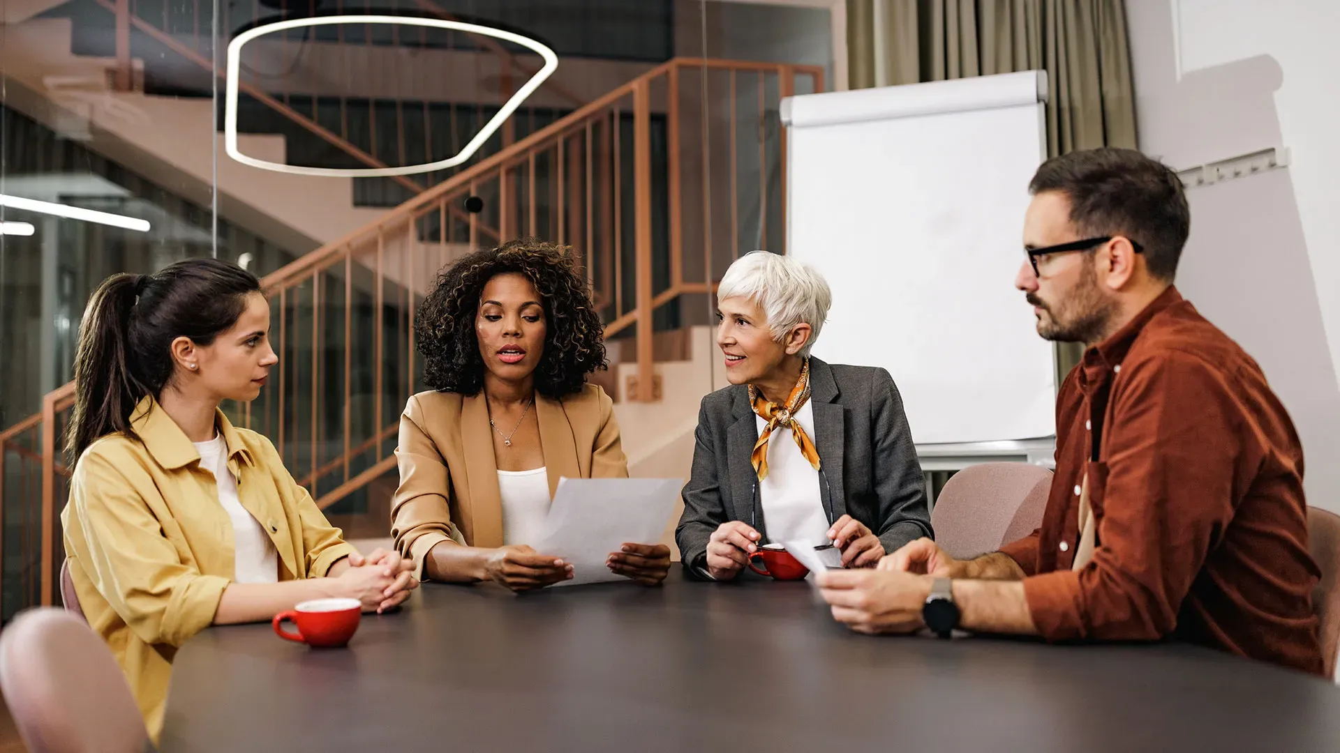 A group of business professionals engaged in discussion around a conference table.